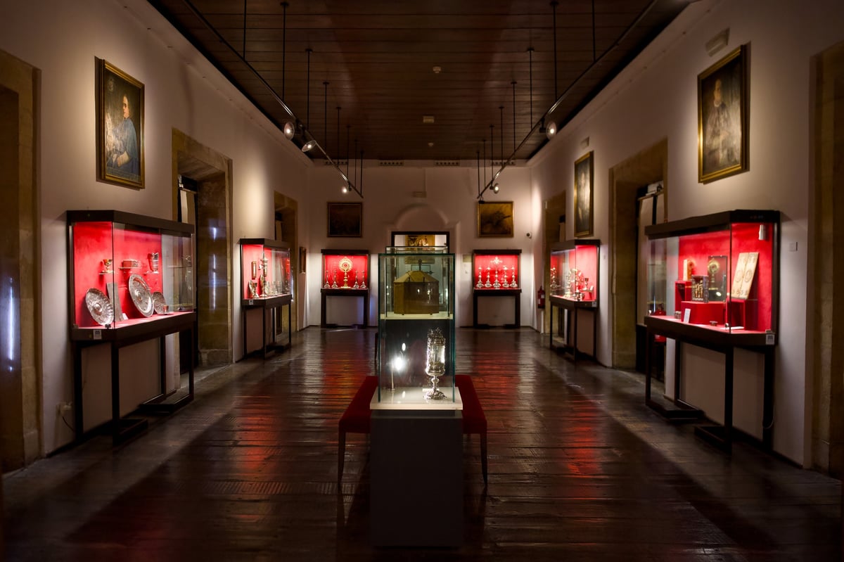 Museum exhibition hall with illuminated display cases showcasing religious artifacts and sacred art